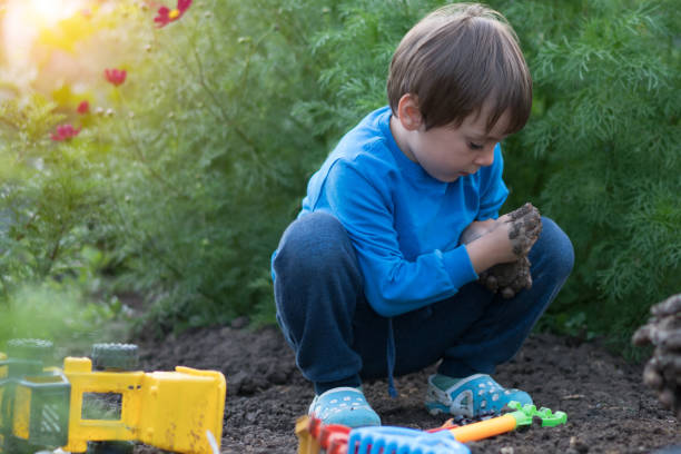 istock Happy boy plays in the mud with his toy 1164760936