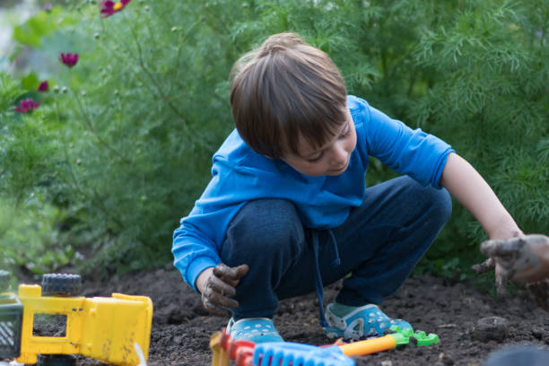 istock Happy boy plays in the mud with his toy 1164761490