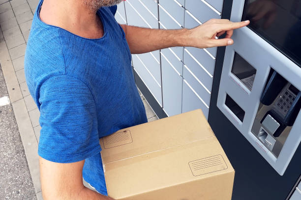 istock Client using automated self service post terminal machine or locker to deposit a parcel for storage 1164761860