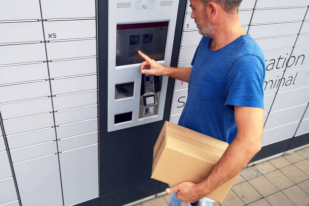 istock Client using automated self service post terminal machine or locker to deposit a parcel for storage 1164761866