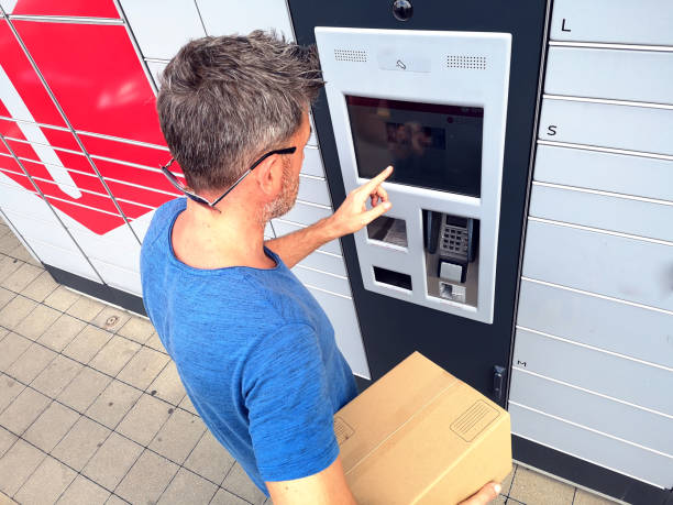 istock Client using automated self service post terminal machine or locker to deposit a parcel for storage 1164761869