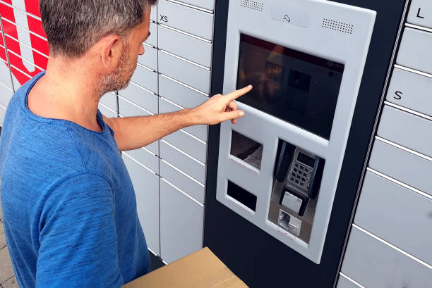 istock Client using automated self service post terminal machine or locker to deposit a parcel for storage 1164761876
