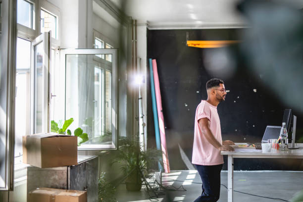 Mixed Race Businessman Moving into New Office on Weekend Mid adult mixed race businessman moving into a new office and standing at a desk as he studies the space. messy vs clean desk stock pictures, royalty-free photos & images