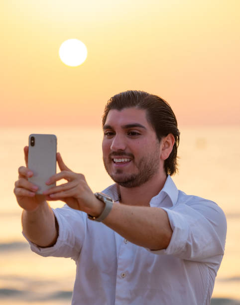 istock Man enjoying colorful sunset or sunrise, taking selfie 1164763003