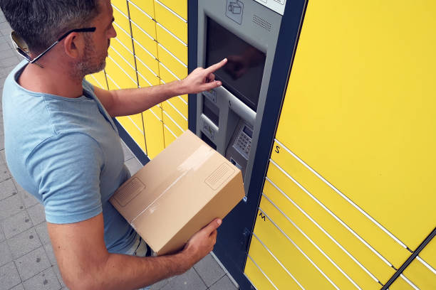 istock Man client using automated self service post terminal machine or locker to deposit the parcel for storage 1164763343