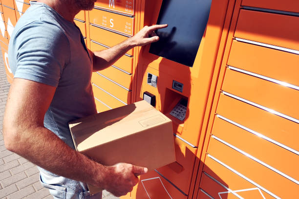 istock Man client using automated self service post terminal machine or locker to deposit the parcel for storage 1164763345