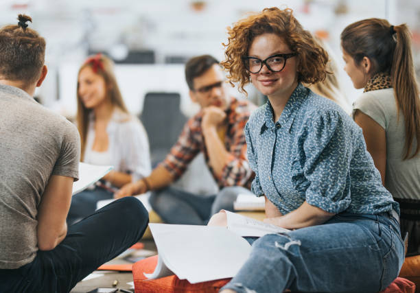 istock Smiling redhead student learning with her friends at campus. 1164764736