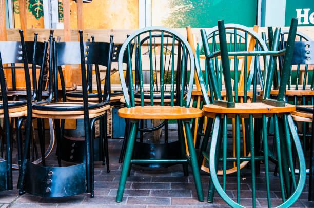 Wooden chairs stacked upside down outside a pub.