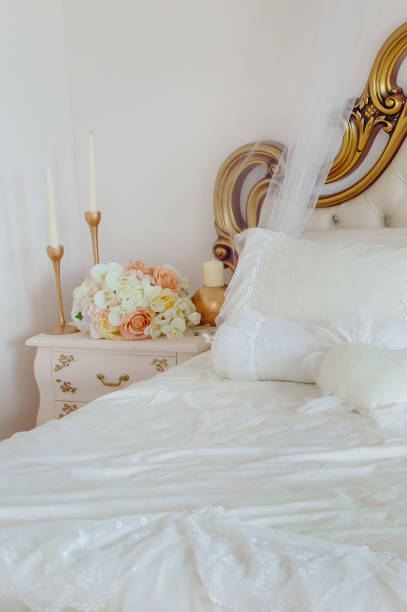 fragment de lit et table de chevet avec des fleurs et des bougies. intérieur élégant de chambre à coucher. - bedroom bed comfortable double bed photos et images de collection