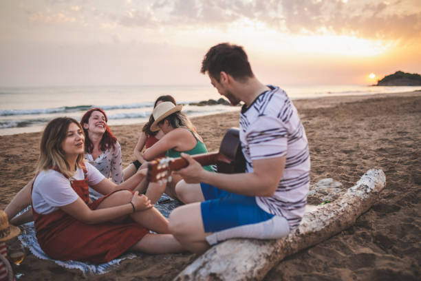 istock Hipster guy playing guitar for friends at the beach 1164765972