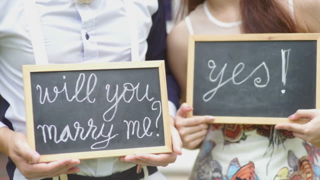 Will you marry me question and yes with handwriting on blackboard shown by the wedding couple.