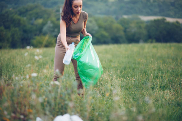 istock Female volunteer picks up trash in park 1164766228
