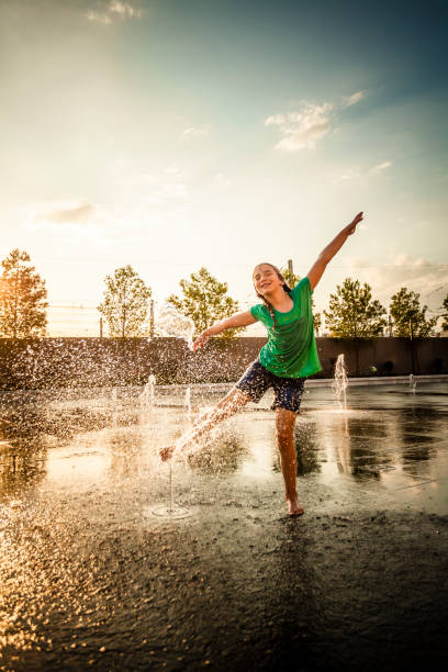 маленькая девочка играет в фонтанах на открытом площадку всплеск - dancing fountains стоковые фото и изображения