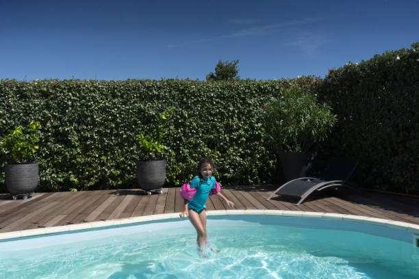 istock 7-year-old girl jumping into pool 1164769004