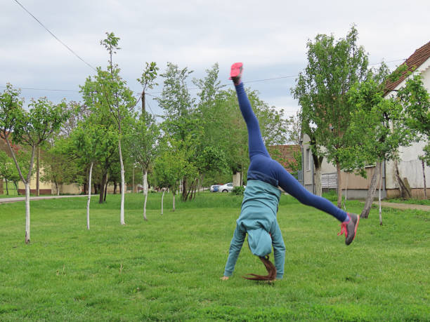 istock A Young Acrobatic Girl Makes a Star on a Grassy Surface in Nature 1164770088