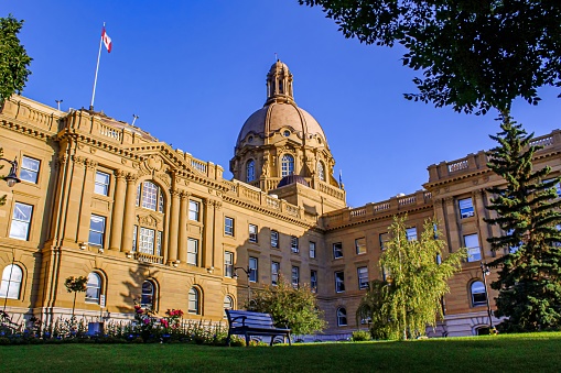 A scenic park bench in front of the historical Alberta Legislature building in Edmonton