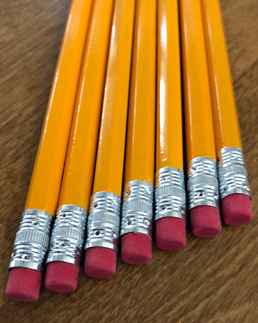 Group of yellow pencils on a wooden desk.