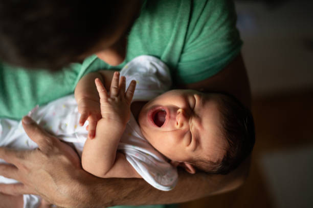 istock Newborn baby yawning in father's hands 1164785361