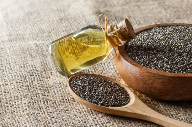 Glass bottle of chia oil and Chia seeds ( Salvia Hispanica ) in wooden spoon and bowl on burlap sack backdrop Glass bottle of chia oil and Chia seeds ( Salvia Hispanica ) in wooden spoon and bowl on burlap sack backdrop. Cereal healthy food contains omega 3, a dietary supplement gluten free salvia hispanica plant stock pictures, royalty-free photos & images