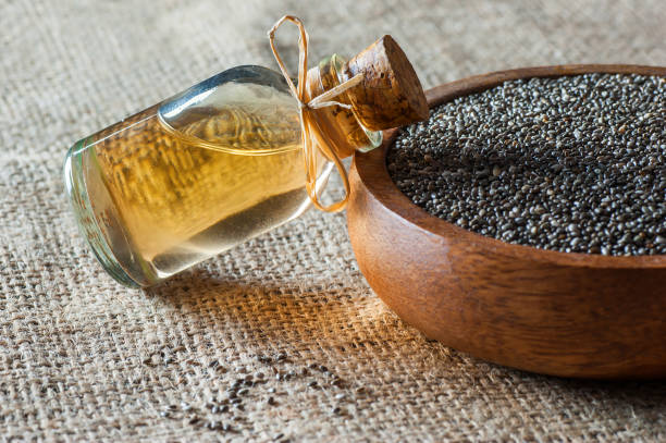 Glass bottle of chia oil and Chia seeds ( Salvia Hispanica ) in wooden bowl on burlap sack backdrop Glass bottle of chia oil and Chia seeds ( Salvia Hispanica ) in wooden bowl on burlap sack backdrop. Cereal healthy food contains omega 3, a dietary supplement gluten free salvia hispanica plant stock pictures, royalty-free photos & images