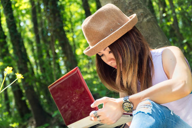 istock University student studying with laptop at campus in woods 1164794905