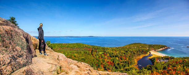 Hiker enjoying the panoramic view from the top of Beehive Trail in Acadia stock photo