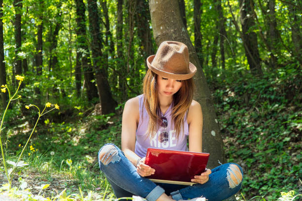 istock University student studying with laptop at campus in woods 1164797483