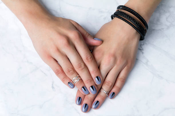 istock Two female hands with creative minimal manicure at white marble 1164798603