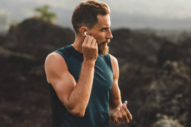 homem que usa vagens de ar sem fio dos auriculares em funcionar ao ar livre. conceito ativo do estilo de vida. - sports music - fotografias e filmes do acervo