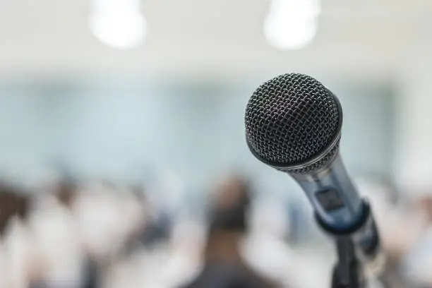 Photo of Microphone voice speaker with audiences or students in seminar classroom, lecture hall or conference meeting in educational business event for host, teacher, or coaching mentor