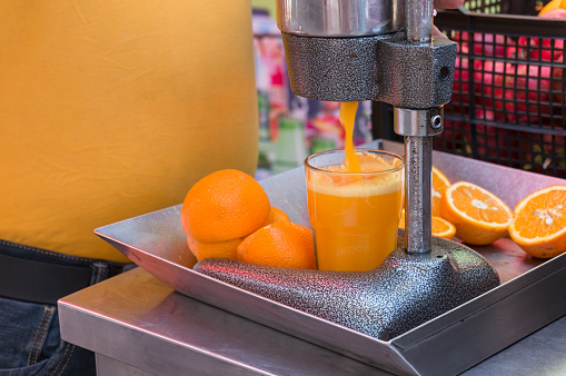 Mechanical juice press. Making orange juice using squeezing machine. Food industry object