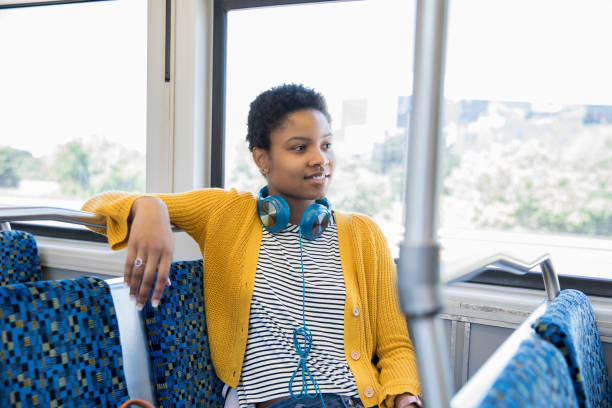 istock Young woman smiles while riding commuter train in the city 1164802525