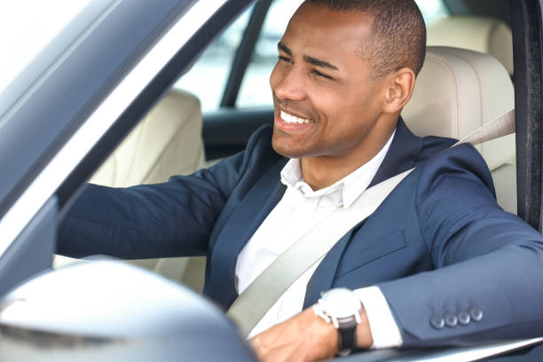 istock Young businessman driver sitting inside car driving looking at road cheerful side view in window close-up 1164802647