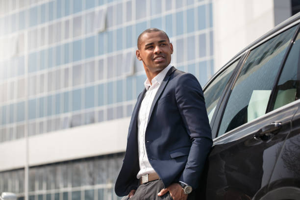 istock Young man standing near car hands in pockets looking aside pensive side view 1164802723