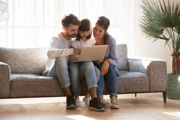 istock Young parents relax on couch using laptop with little daughter 1164802810