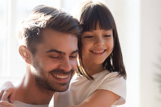 istock Smiling little daughter hug young dad at home 1164802817
