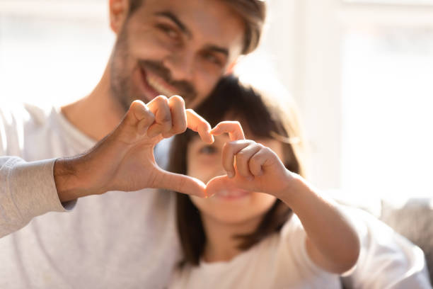 istock Happy young dad and little daughter make heart hand gesture 1164802821