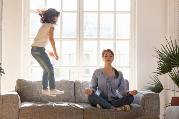 istock Mom meditating on couch ignore kid jumping near 1164802848