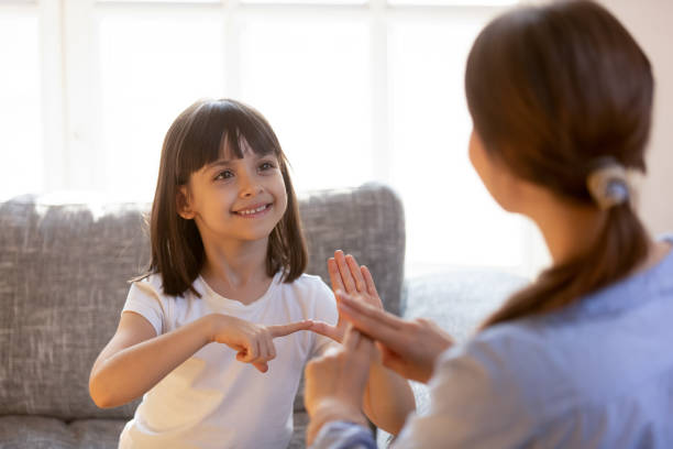 Cute little girl practice sign language with teacher Cute little girl make hand gesture learning sign language with mom or female nanny, smiling small kid practice nonverbal talk with teacher at home, preschooler disabled child have lesson with tutor deaf stock pictures, royalty-free photos & images