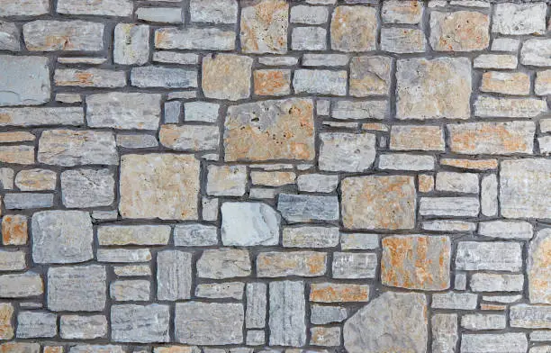 Grey stone wall with interesting texture of stones. Vintage background of grey wall.