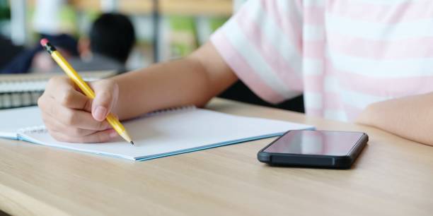 istock Online learning home school concept, Close up of college student hand writing notebook and smartphone on table, College education and communication in campus, Home school online education, E learning 1164817210