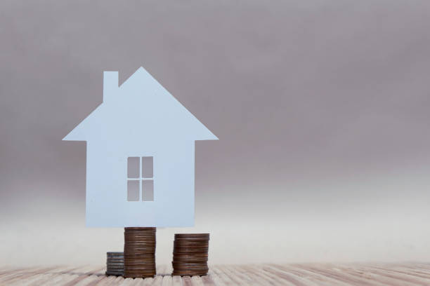 istock The concept of home from paper on a stack of coins. Horizontal composition. 1164817348