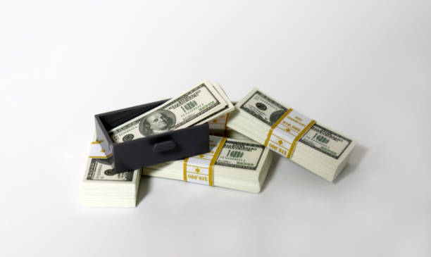 istock A bunch of $ 100 bills and a miniature gray drawer. 1164819416