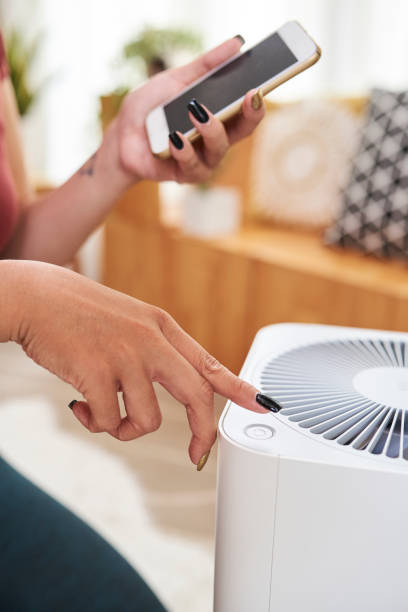 istock Woman turning on fan 1164821392