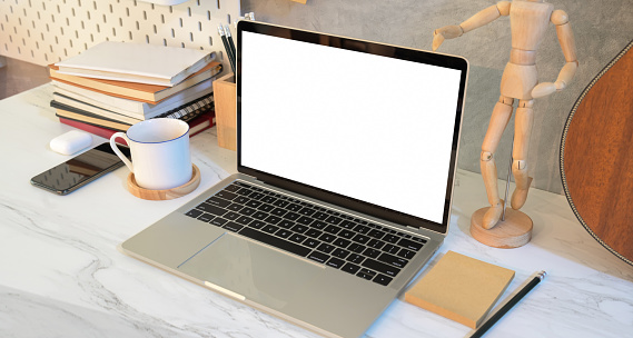 professional designer's work place with blank screen laptop on marble table with grey wall background
