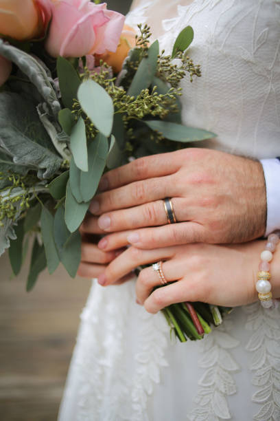 istock Newlywed Bride and Groom Displaying their New Wedding Rings while Carrying a Bouquet 1164829861