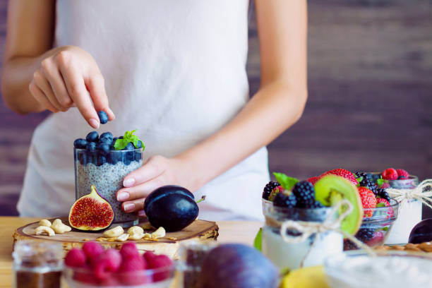 Healthy fitness food for breakfast Female hands are preparing yogurt with chia and blueberries for good digestion, functioning of gastrointestinal tract. Summer berries, nuts, fruits, dairy products on table. Healthy food concept. fig photos stock pictures, royalty-free photos & images