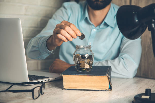 istock man hand coin with jar on book 1164836179