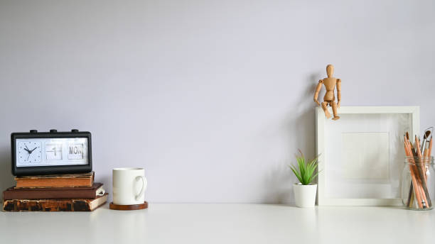 istock Workspace photo frame, coffee, alarm, books with plant decorate on white table. 1164836994