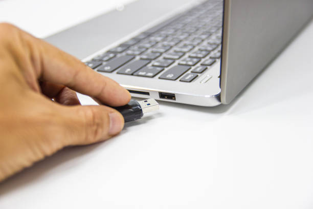 istock hand man hold Flash drive connect to USB port plug-in computer laptop for transfer data 1164838112